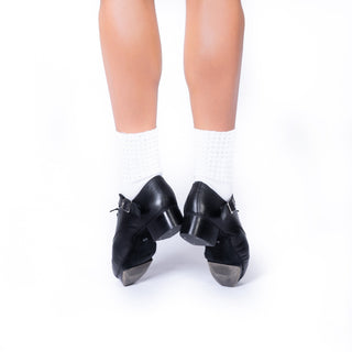 Heel view of black jig shoes on feet showing metal taps and straps