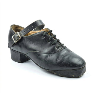 Repaired black leather jig shoe with stitched patch covering toe damage